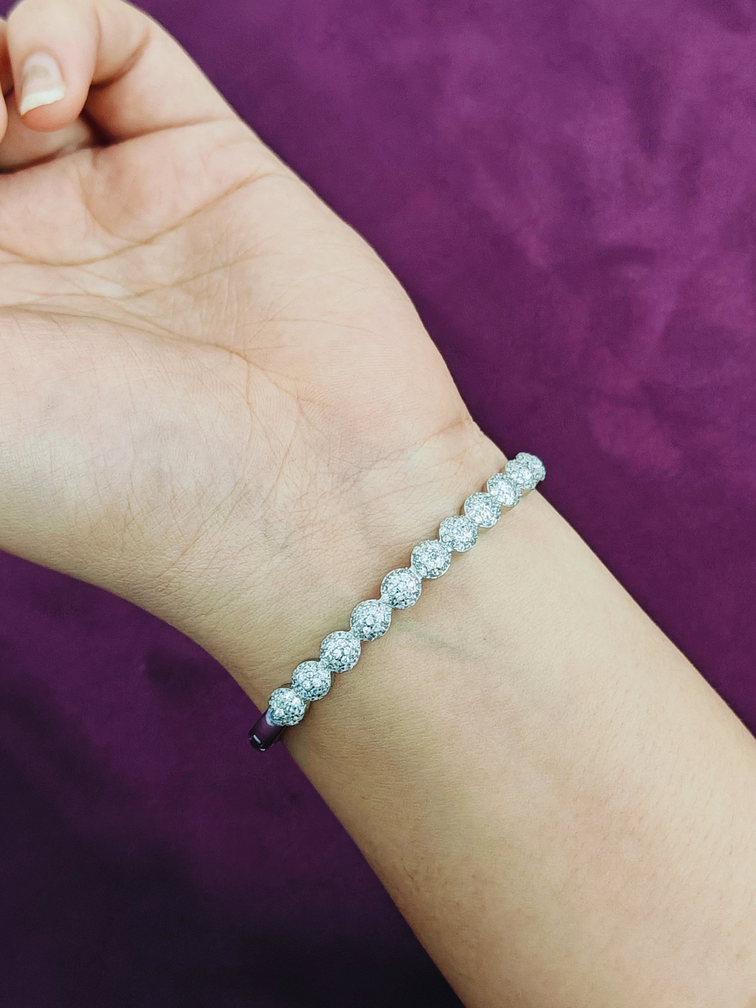 Silver bracelet on a wrist against a purple background